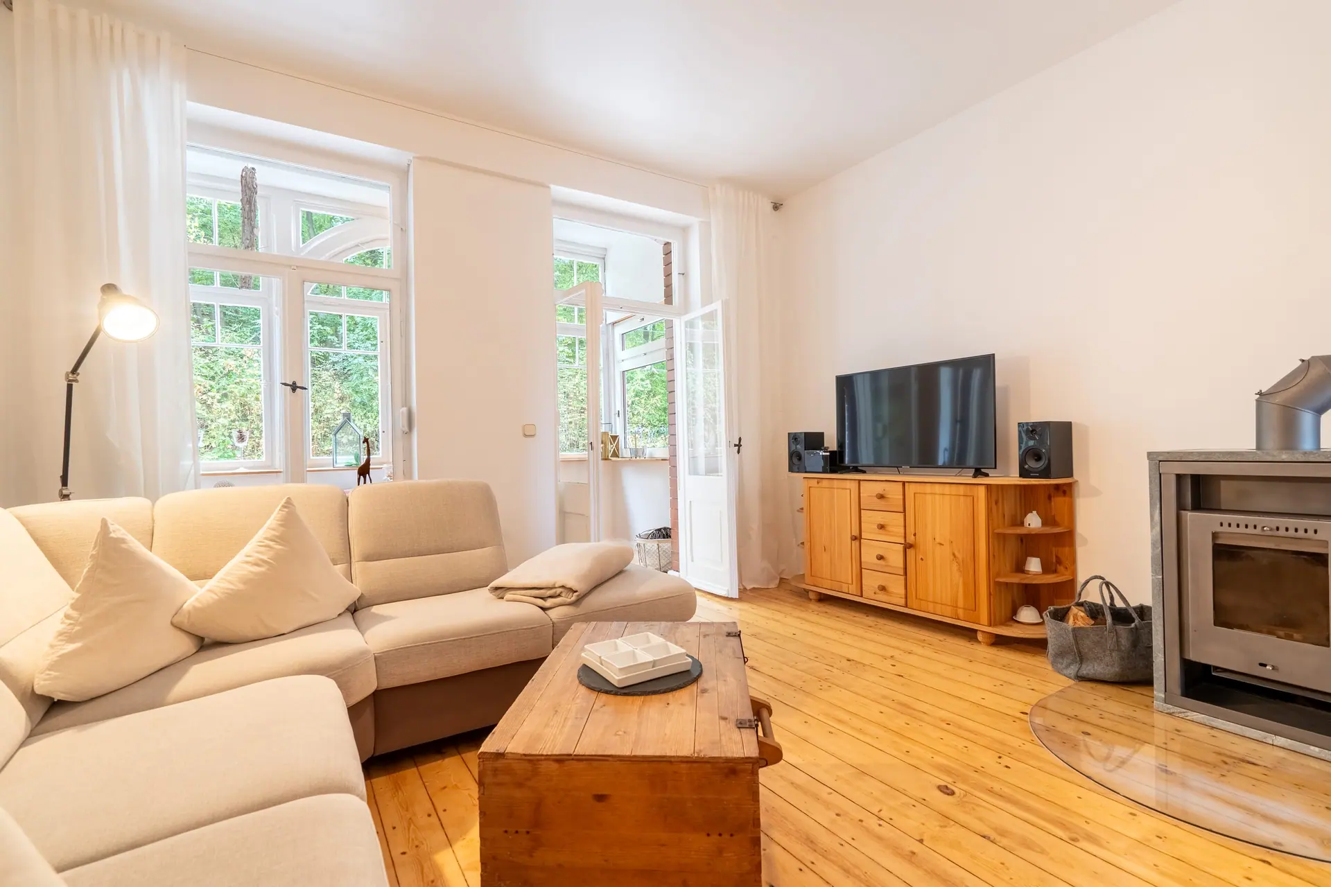 Wohnzimmer mit Sofa, Fernseher auf einer Holzkommode und Ofen
